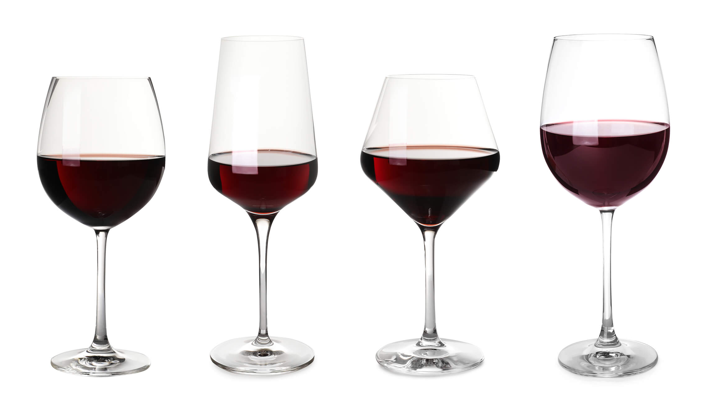 Four glasses of red wine in glasses of different shapes and styles neatly lined up against a white background