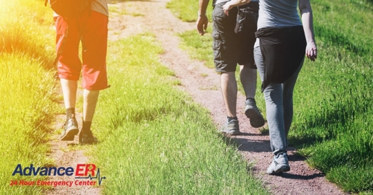 three people walking away from camera on dirt path
