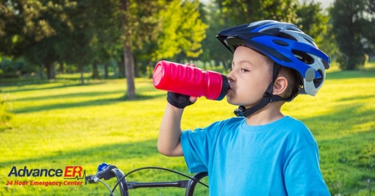 child drinking water with bike helmet on