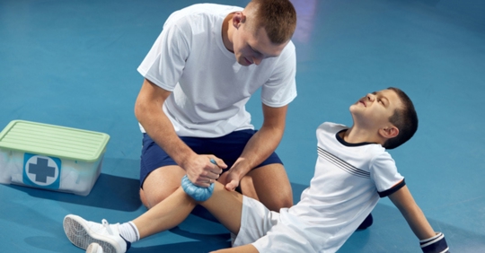 Coach icing an athlete's knee