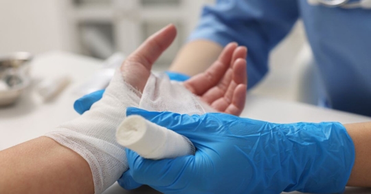 Doctor wrapping a man's hand in gauze dressing.