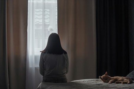 Woman sitting in a dark bedroom with her cat on a dreary winter day. | Advance ER