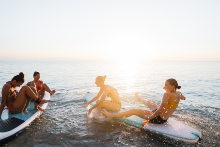 Group of friends hanging out on surfboards in the ocean on spring break.