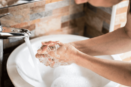 man washing his hands over a sink with running water and soap