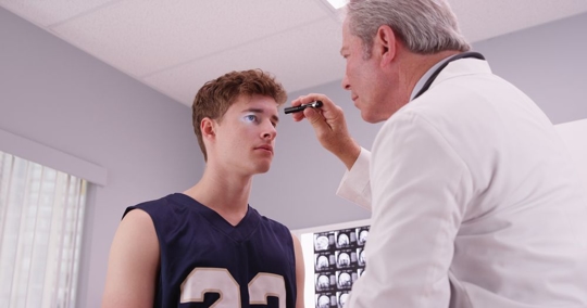 older doctor examining young athlete