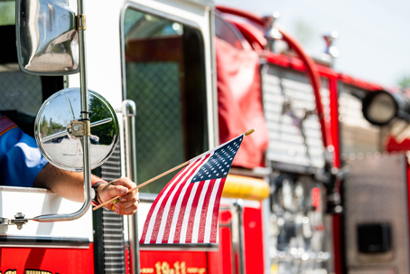 Firefighter holding American flag from fire truck during first responder appreciation