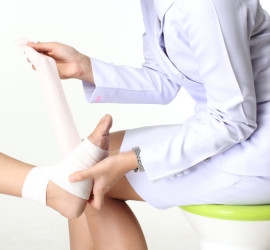 Doctor holding patient's wrapped ankle