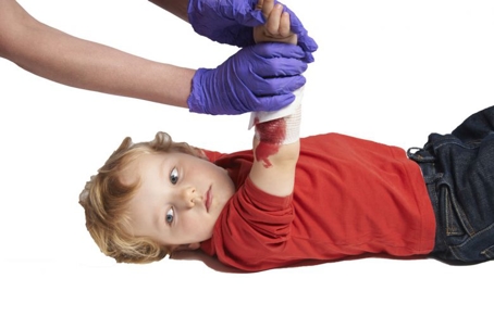 Adult putting pressure on bleeding cut on child's arm