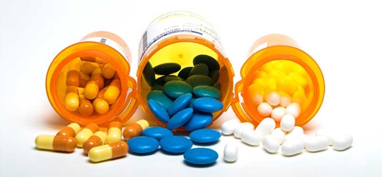 Three different pills spilling out of their bottles